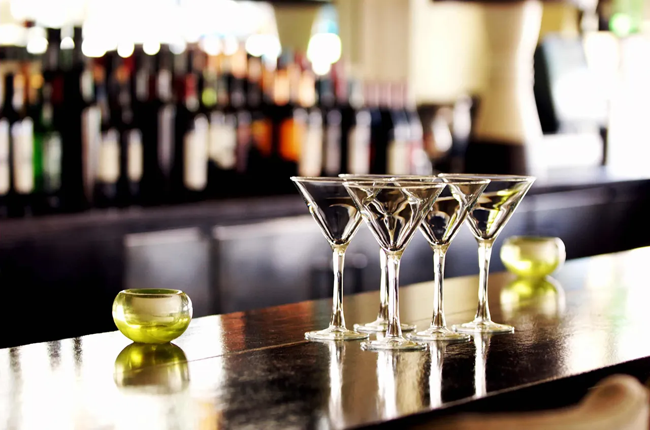Female bartender standing in front of a liquor shelf